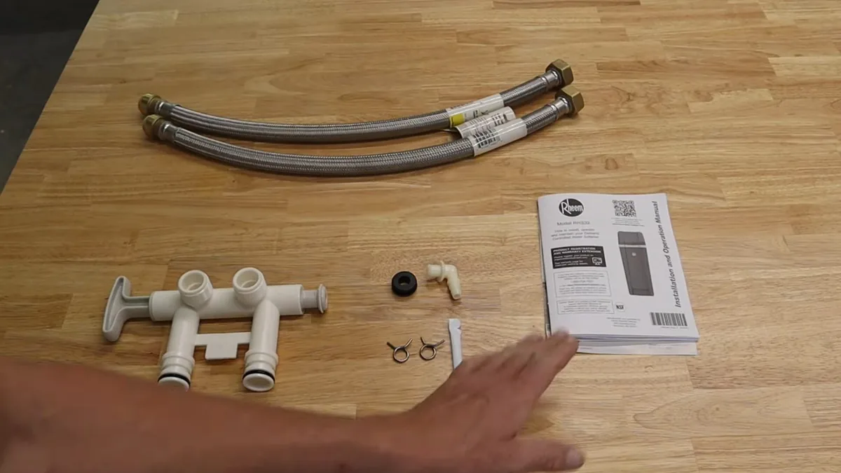 Two braided supply hoses, white valve parts, small fittings and an instruction booklet laid out on a wooden table