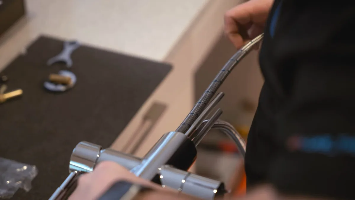Hands guiding a braided hose onto a chrome kitchen faucet fitting laid on a counter