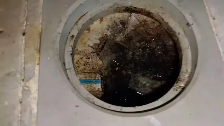 Round cleanout opening set in a concrete floor with dark standing water inside