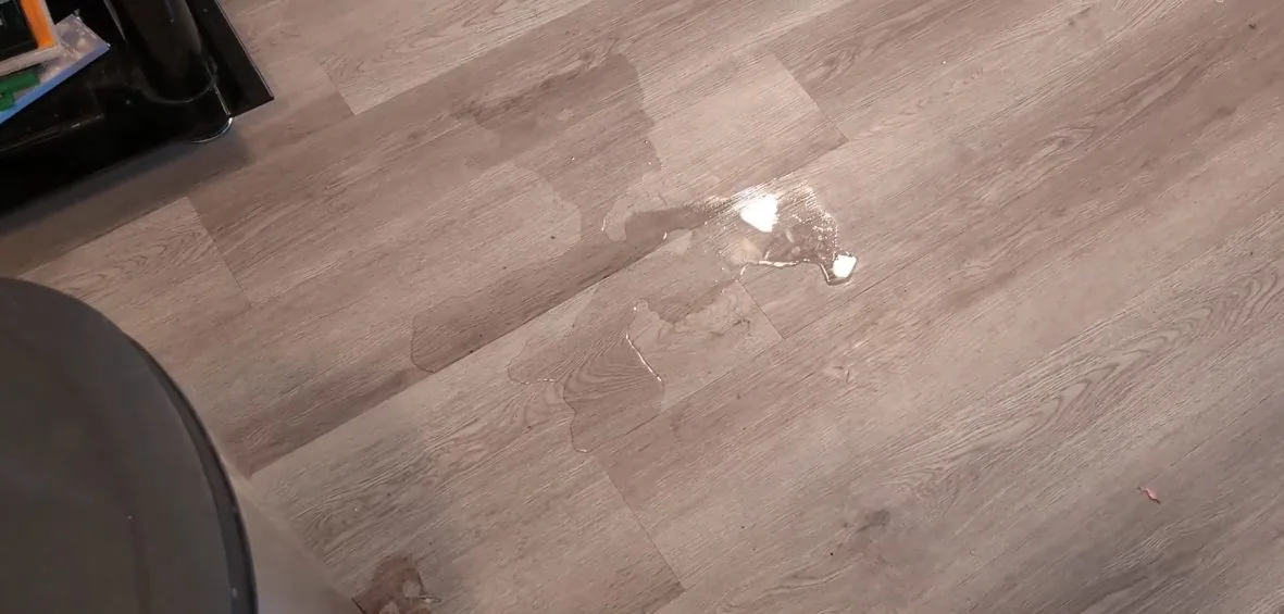 Small pool of water on a wood-effect floor beside the edge of an appliance