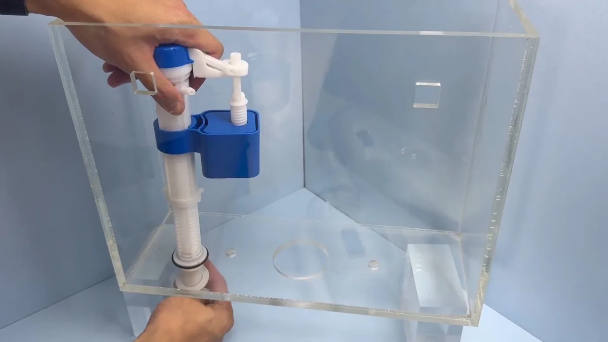 Clear tank showing a blue-topped fill valve and float being adjusted by hand